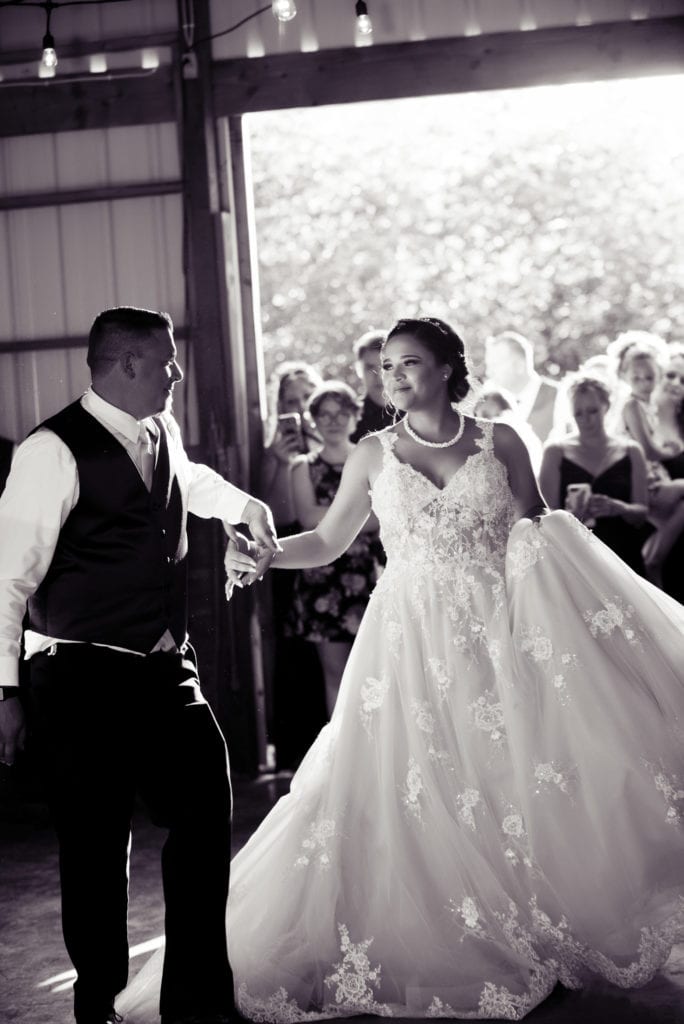 the bride and groom have their first dance in a barn in brush prairie and the bride's large dress twirls