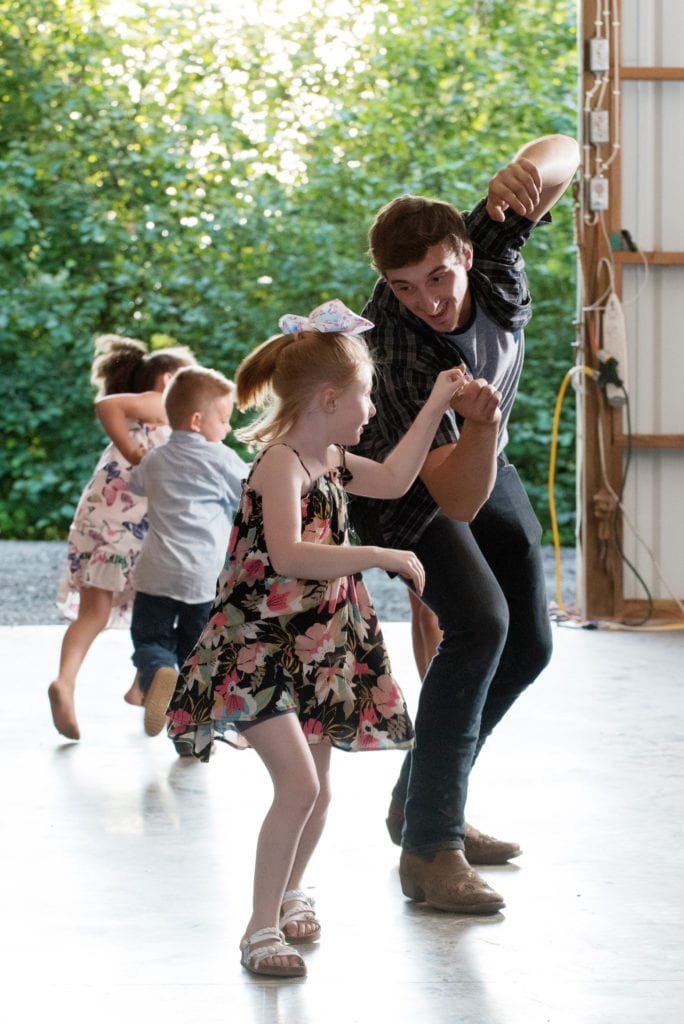 a man dances with a young girl during a wedding reception in a barn in washington state
